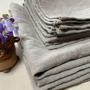 May include: A stack of gray linen kitchen towels folded neatly. The towels are made of a soft, natural fabric and have a subtle texture.