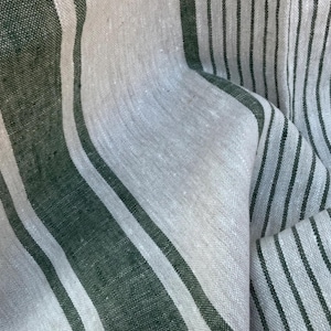 May include: A woven fabric featuring a pattern of alternating wide dark forest green stripes and narrower off-white stripes. The textile has a visible, slightly coarse, natural fibre texture with vertical lines running throughout the material.