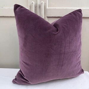 May include: A plush purple velvet cushion with a square shape. The cushion is soft and comfortable, perfect for adding a touch of luxury to any room.
