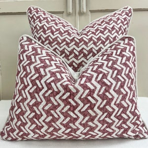 May include: Two decorative throw pillows with a geometric pattern in shades of burgundy and white.