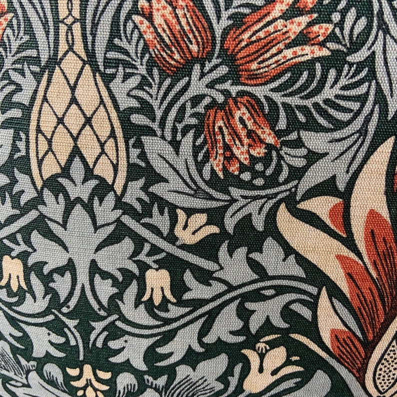 May include: A close-up of a fabric with a repeating pattern of stylised flowers and leaves in shades of green, brown, and cream. The fabric has a textured surface.