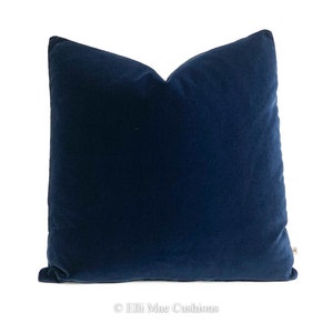 May include: A deep blue velvet cushion cover. The cover is made from a soft, luxurious fabric and has a simple, elegant design.