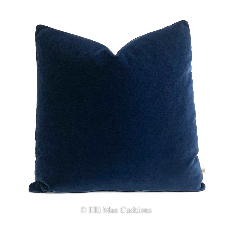 May include: A deep blue velvet cushion cover. The cover is made from a soft, luxurious fabric and has a simple, elegant design.