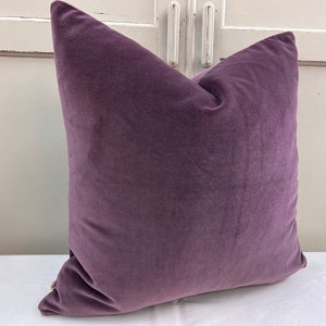 May include: A soft, plush purple velvet cushion cover. The cushion is square and has a simple, elegant design.