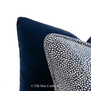 May include: Close-up of a navy blue velvet cushion with a white polka dot patterned cushion on top. The polka dot cushion has a navy blue border.