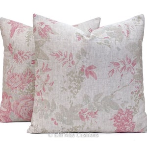 May include: Two square throw pillows with a light gray linen fabric background and a pink floral pattern. The pillows are arranged side by side with the floral pattern facing outward.