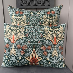 May include: Two decorative throw cushions featuring a green, cream and red floral pattern. The cushions are made from a soft, textured fabric.