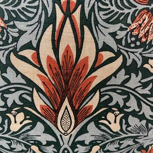 May include: A close-up of a fabric with a repeating pattern of stylised flowers in shades of green, brown, and cream. The flowers have a detailed design with intricate lines and curves.