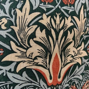 May include: Close-up of a fabric with a repeating pattern of stylised flowers in shades of beige, green, and orange. The fabric has a textured surface.