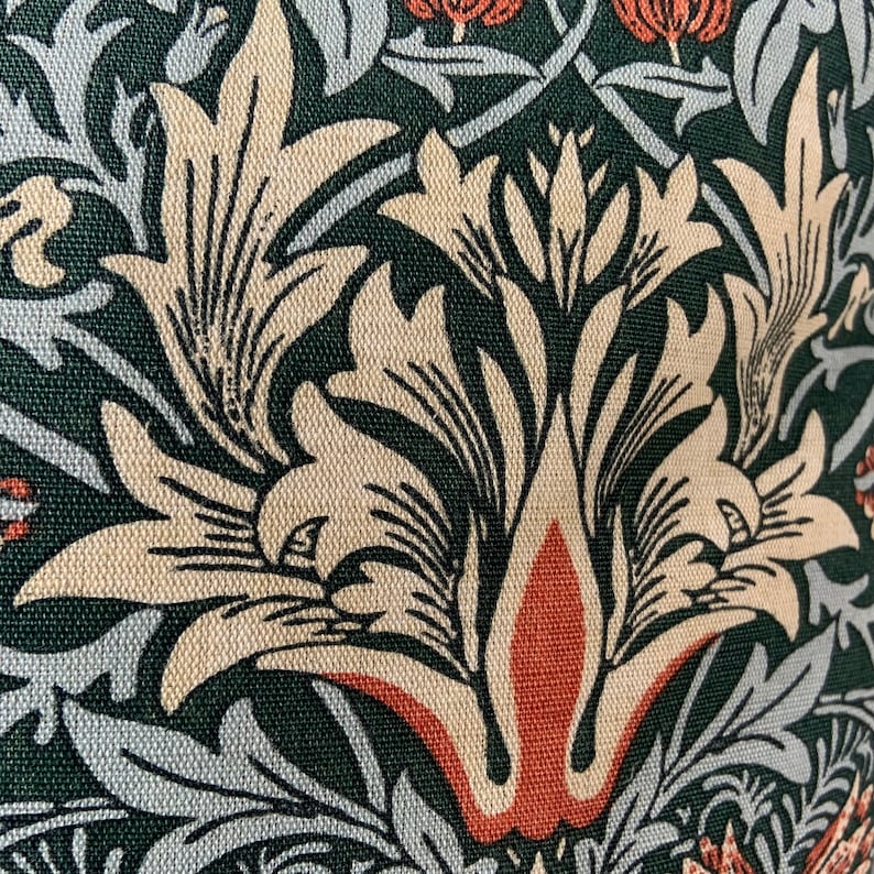 May include: Close-up of a fabric with a repeating pattern of stylised flowers in shades of beige, green, and orange. The fabric has a textured surface.