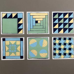 May include: Six square art prints with geometric designs. Each print features a different pattern in shades of blue, yellow, and green, outlined in black. The prints are mounted on a gray background.