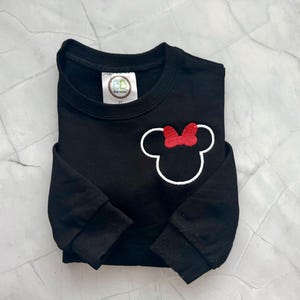 Op de afbeelding: Zwart sweatshirt met een witte omtrek van een muizenkop en een rode strik. De sweatshirt heeft lange mouwen en een ronde hals. Het label leest "BB Kids Design" en "3T".