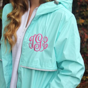 May include: A light blue rain jacket with a pink monogrammed initial "JGB" on the left chest.