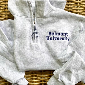 May include: A gray sweatshirt with a zipper and a navy blue embroidered logo that says "Belmont University".