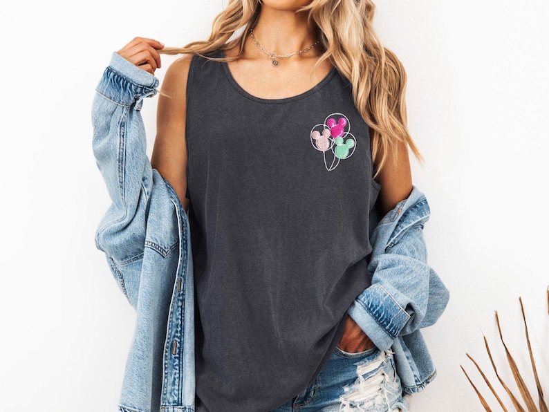 May include: Dark gray tank top with a crew neck. The shirt features a design of three Mickey Mouse head-shaped balloons in pink, mint green, and light pink. The balloons are connected by thin white strings.
