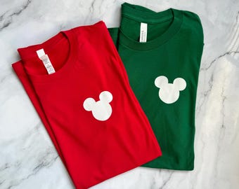 May include: Two t-shirts, one red and one green, with a white Mickey Mouse silhouette on the front.