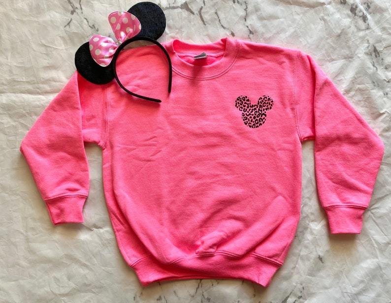 May include: A pink sweatshirt with a black and white leopard print Mickey Mouse head design on the front.