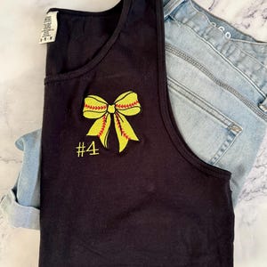 Op de afbeelding: Zwart tanktop met een gele softbal strik en het nummer 4 geborduurd op de voorkant.