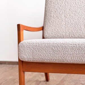 Puede incluir: Sill&oacute;n moderno de mediados de siglo con asiento y respaldo de tela texturizada gris claro. La silla tiene una estructura de madera maciza con un acabado marr&oacute;n rojizo c&aacute;lido. Los reposabrazos se curvan suavemente y las patas son rectas.