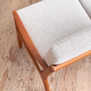 Puede incluir: Un sof&aacute; de dos plazas de estilo moderno de mediados de siglo con tela texturizada gris claro y un marco de madera. El marco de madera tiene un acabado c&aacute;lido y natural. El sof&aacute; tiene un dise&ntilde;o simple y minimalista, con l&iacute;neas limpias.