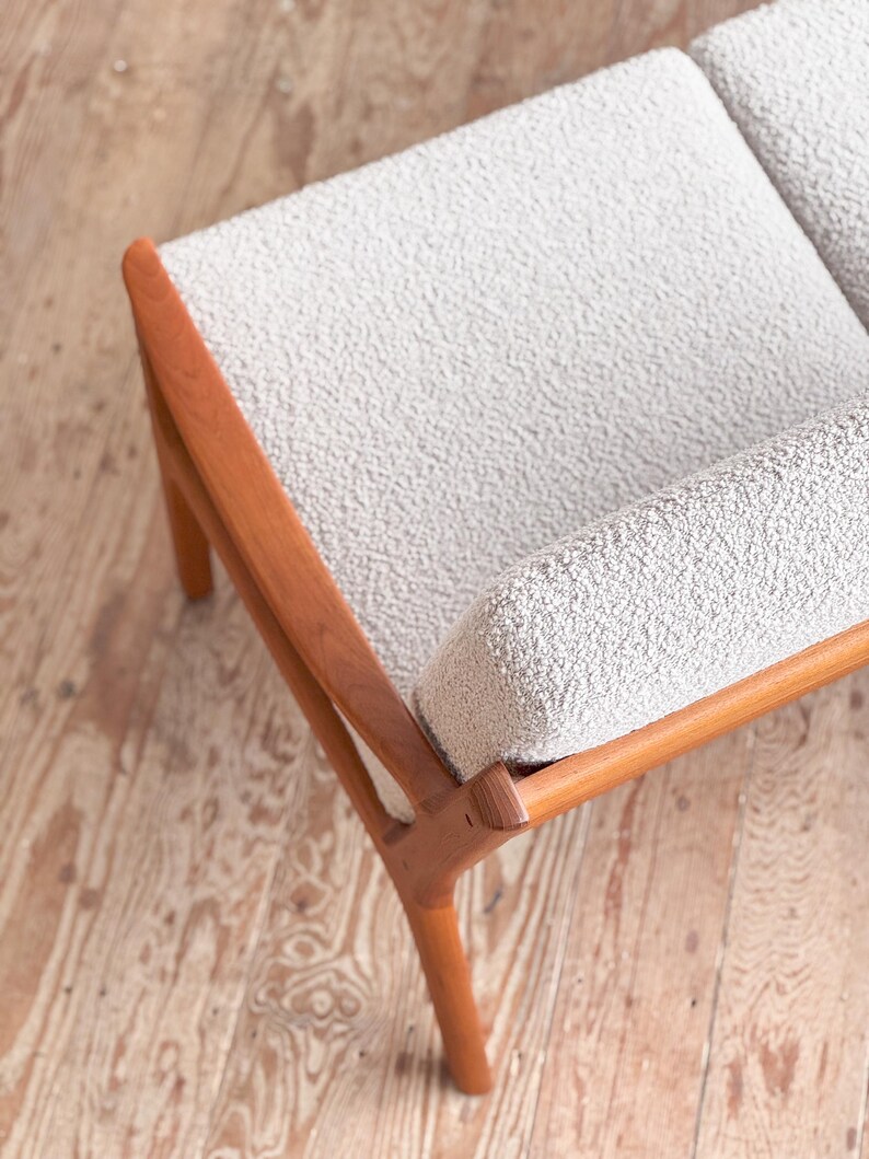 Puede incluir: Un sof&aacute; de dos plazas de estilo moderno de mediados de siglo con tela texturizada gris claro y un marco de madera. El marco de madera tiene un acabado c&aacute;lido y natural. El sof&aacute; tiene un dise&ntilde;o simple y minimalista, con l&iacute;neas limpias.