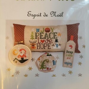 May include: Cross stitch pattern for a Christmas pillow, ornament, and bookmark. The pillow features the words "Joy, Peace, Love, Hope" with a snowman, reindeer, and other Christmas imagery. The ornament features a Christmas tree and the bookmark says "Keep calm and enjoy".