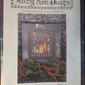May include: A cross-stitch pattern from Waxing Moon Designs, featuring a framed image with the text "Silent Night, Holy Night." The design includes a house, trees, and stars, with a garland of red beads at the bottom. The pattern is labeled #015.