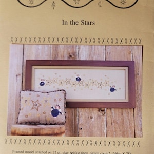 May include: A cross-stitch pattern for a framed design titled "In the Stars" by Bent Creek. The design features a row of stars with a small angel in each star. The pattern is stitched on 32 count clay belfast linen and measures 16.6 inches by 4.7 inches. The pattern also includes a pillow model stitched on 10 count natural heatherfield and measures 10.1 inches by 6.7 inches.