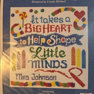 May include: Cross-stitch kit with the text "TEACHERS HAVE A BIG HEART" and "It takes a BIG HEART to Help Shape Little MINDS Mrs Johnson". The design includes colorful hearts, crayons, and a rainbow.