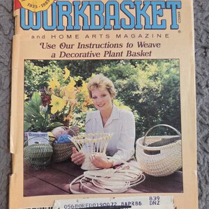 May include: The cover of a vintage Workbasket magazine from September 1985. The cover features a woman holding a decorative plant basket, with other woven baskets and flowers in the background. The magazine's title and issue details are visible.