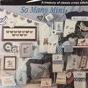 May include: A collection of cross-stitch designs, including framed hearts, angels, and animals. The image features the text "So Many Minis" and "Jeanette Crews Designs". The designs are displayed on various items, such as towels and pillows.