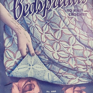 May include: A vintage book cover for a crochet pattern book titled "Bedspreads to Knit and Crochet". The cover features a close-up of a crocheted bedspread with a delicate floral pattern in shades of blue and brown. The book number is 186 and the price is 10 cents.