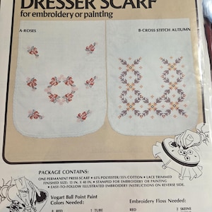 May include: A Vogart Crafts package for a dresser scarf, featuring two designs: A-Roses and B-Cross Stitch Autumn. The package includes a 13 in. x 40 in. permanent press scarf, stamped for embroidery or painting. Colors needed are listed.