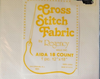May include: Off-white cross stitch fabric by Regency Mills Inc. The label reads "Cross Stitch Fabric" in yellow, with a needle and thread graphic. The fabric is AIDA 18 count, 12" x 18", and made of 100% cotton. A Target price tag is visible.