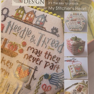 May include: A cross-stitch pattern titled "My Stitcher's Heart" with the text "Needle & Thread may they never part." The design includes houses, keys, and scissors. The image also shows a small box, a pincushion, and a small bag.