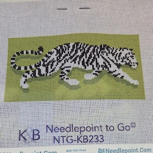 May include: A needlepoint canvas featuring a black and white tiger graphic on a solid light green rectangular background. The canvas includes the printed text KB Needlepoint to Go NTG-KB233 at the bottom, with a grid pattern throughout the fabric.