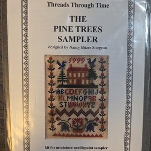May include: A kit for a miniature needlepoint sampler titled "The Pine Trees Sampler" by Nancy Bitzer Sturgeon. The design is approximately 1.5" x 2" and includes a house, trees, birds, and the alphabet. The kit includes silk gauze, needle, and instructions.