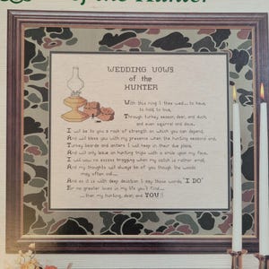 May include: Framed artwork featuring the text "Wedding Vows of the Hunter." The artwork includes a decorative border with a camouflage pattern. The text is in a script font, with illustrations of a lamp and hunting gear.