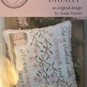 May include: Cross-stitch kit featuring a floral design with the text "Strength and Dignity" and "She is clothed with strength and dignity". The kit includes the text "The Proper Stitcher" and "Proverbs 31:25".