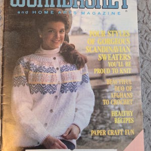 May include: The Workbasket and Home Arts Magazine cover from May 1990. The cover features a woman wearing a white cardigan with a Scandinavian design. The magazine's title is in blue, and the cover includes text about knitting and crochet projects.