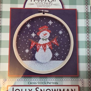 May include: A cross-stitch pattern featuring a snowman design within an embroidery hoop. The snowman wears a red hat and scarf, surrounded by snowflakes. The text "JOLLY SNOWMAN" is displayed below the image, with the Happy Cat Stitchery Sanctuary logo at the top.