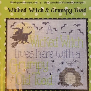 May include: Cross stitch pattern featuring a witch flying on a broomstick with a full moon and bats in the background. The text reads "A Wicked Witch lives here with a Grumpy Old Toad." The pattern is labeled "#ML24" and "A Waxing Moon "Moon-Lite" Design."