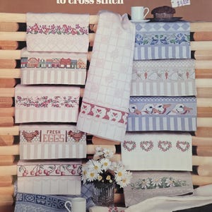 May include: A selection of cross-stitch gourmet towels featuring diverse designs such as flowers, houses, chickens, cherries, and hearts. The towels are arranged on a wooden surface, with the text "GOURMET TOWELS to cross stitch" displayed.