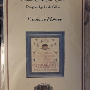 May include: A cross stitch chart titled "Primitive Things" with the design "Prudence Holmes." The chart features a framed sampler with an alphabet, house, and floral motifs. Designed by Linda Gillon.
