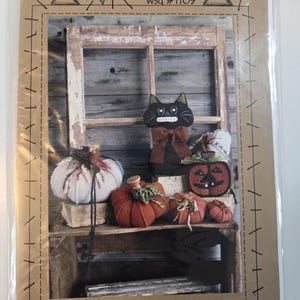 May include: A craft pattern titled Pumpkin Patch Jack wsd #1109 by Wooden Spool Designs. The cover features a black cat plush, several fabric pumpkins in orange and white, and a wooden window frame. The design includes hand-drawn spool illustrations.