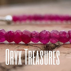 May include: A pink gemstone bracelet with a silver clasp. The bracelet is made of small, faceted beads and is strung on a silver chain.