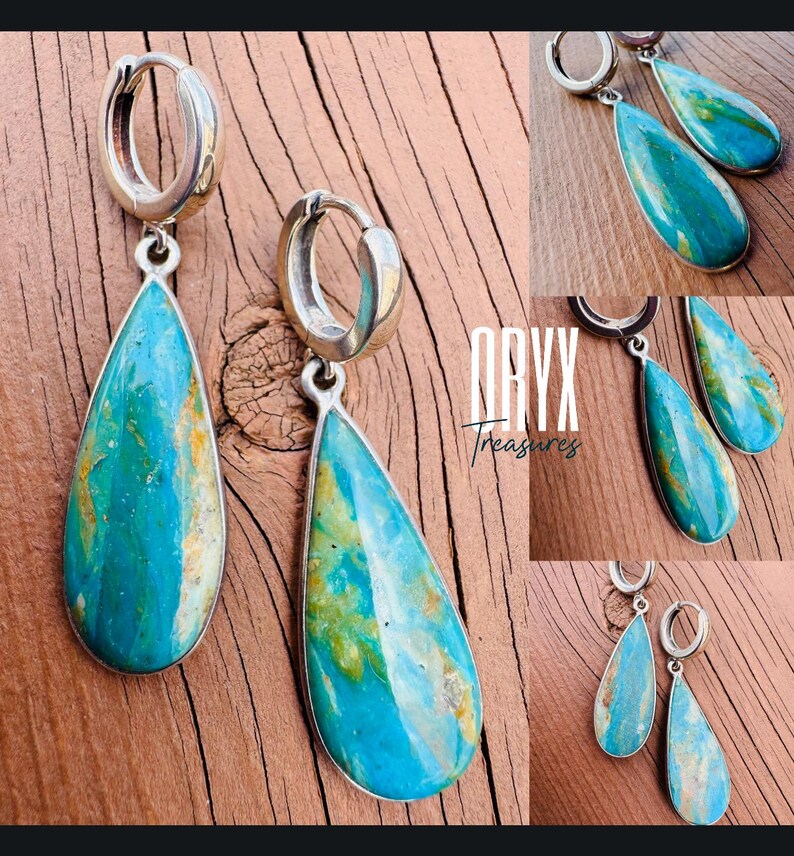 Puede incluir: Pendientes de aro plateados con colgantes de turquesa en forma de l&aacute;grima. La turquesa presenta una mezcla de tonos azules, verdes y marrones. El texto "ORYX Treasures" es visible sobre una superficie de madera.