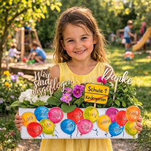 May include: A young girl in a yellow dress holds a white wooden box filled with flowers and balloons. The balloons are painted in various colors and have names written on them. The box also has wooden signs that say "Wir sind ausgeflogen" and "Danke". A sign indicates "Schule" and "Kindergarten".