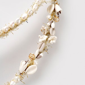 May include: A white pearl and gold beaded headband with white floral and shell embellishments.