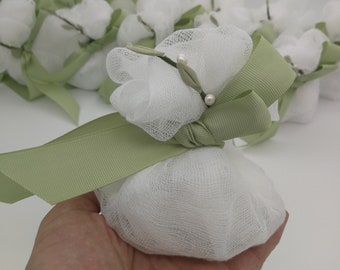 May include: White fabric favor bags tied with a green ribbon and decorated with a sprig of greenery and pearl beads.